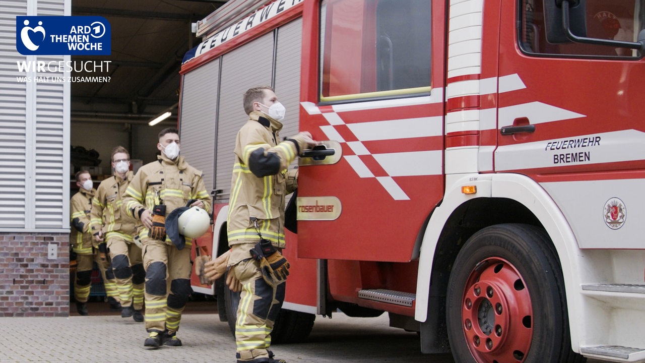 Eine Gruppe Feuerwehrmänner in voller Montur rennt zu einem Feuerwehrauto der Freiwilligen Feuerwehr Neustadt.