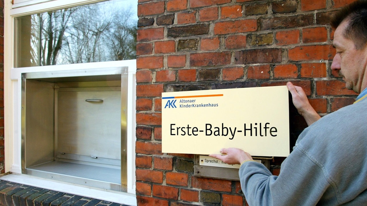 Ein Schild mit der Aufschrift "Erste-Baby-Hilfe" befestigt ein Mitarbeiter des Kinderkrankenhauses in Hamburg-Altona neben der so genannten Babyklappe