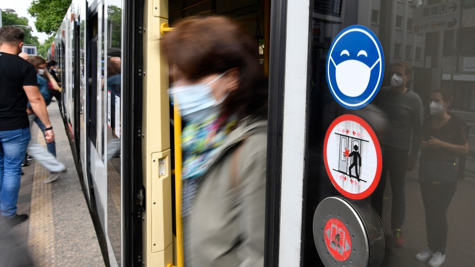 Eine Frau mit medzinischer Maske steigt aus einer Straßenbahn