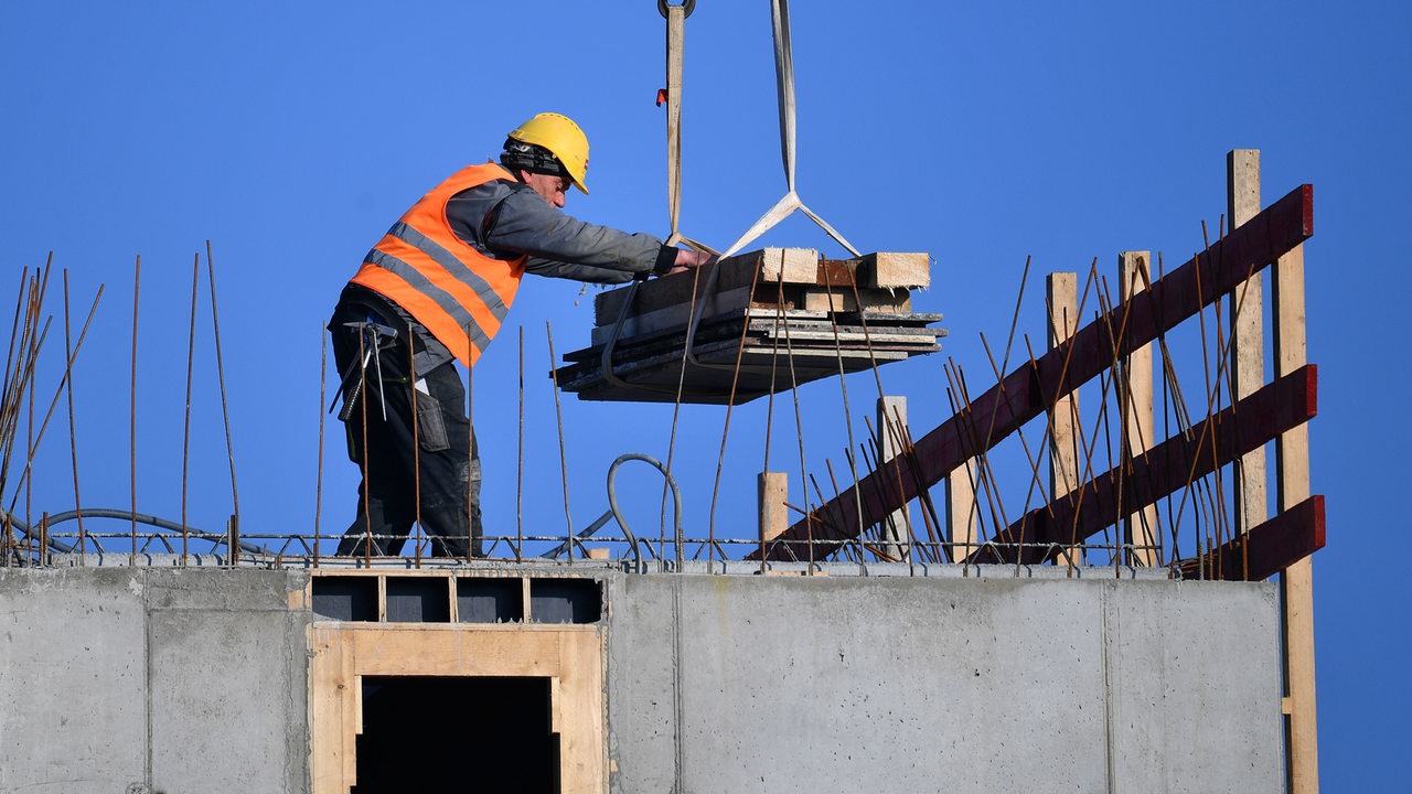 Ein Bauarbeiter arbeitet auf dem Dach eines Rohbaus