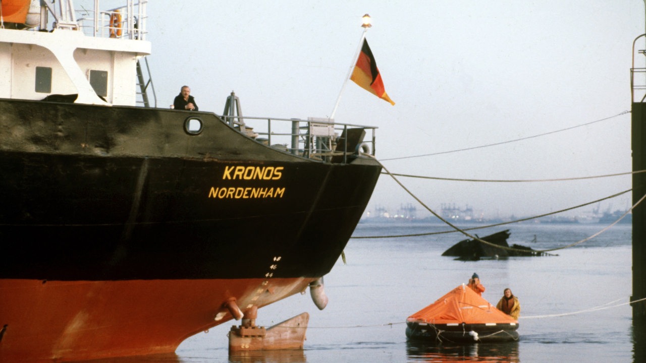 Mitglieder von Greenpeace schwimmen in einer roten Rettungsinsel vor dem Bug des Abfalltankers "Kronos", der in Nordenham auf der Weser vor Anker liegt. (Archivbild)