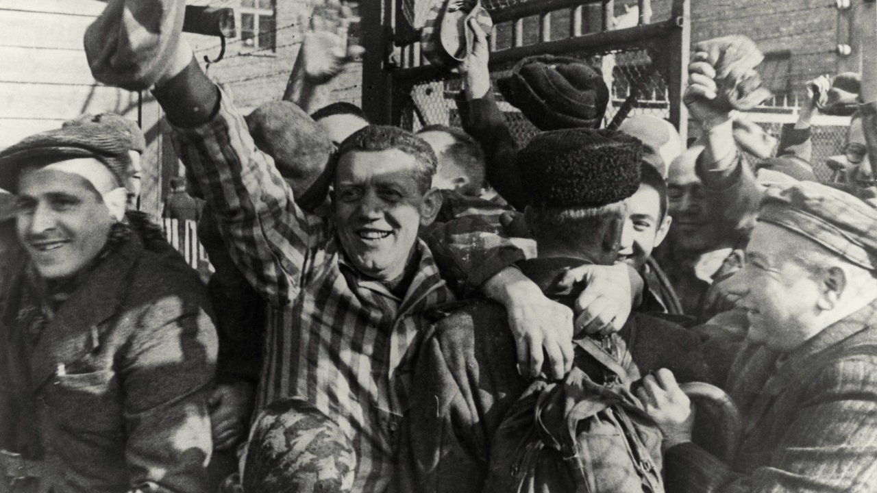 Jubelnde Häftlinge nach der Befreiung durch sowjetische Truppen am Lagertor am 26.1.1945