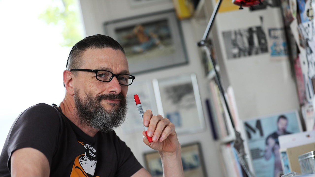 Comic-Zeichner Ralf König sitzt an seinem Schreibtisch