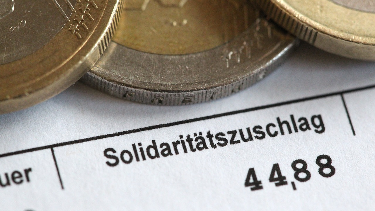Euromünzen auf einer Lohnabrechnung und das Wort Solidaritätszuschlag.