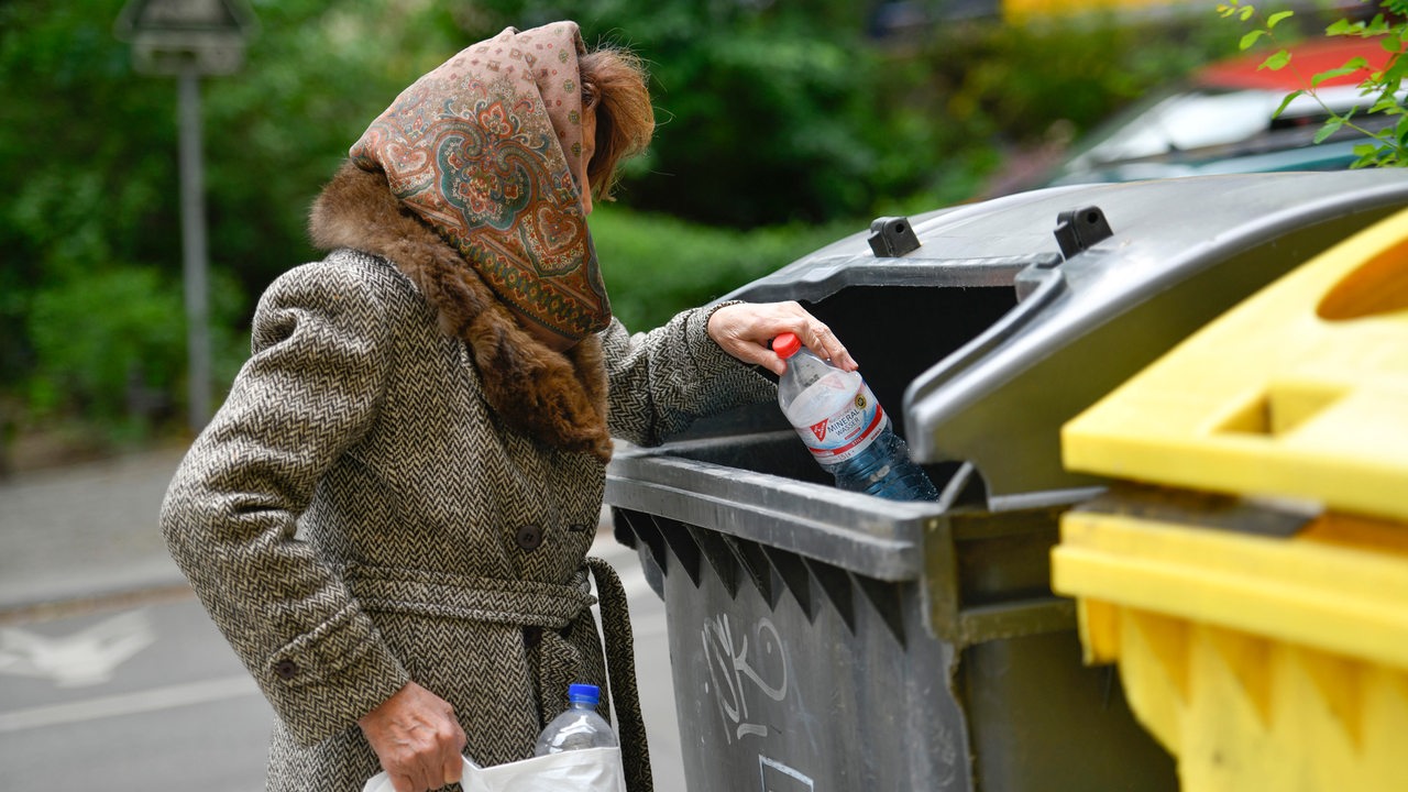Eine Frau sammelt Pfandflaschen aus einem Müllcontainer (gestelltes Symbolbild)