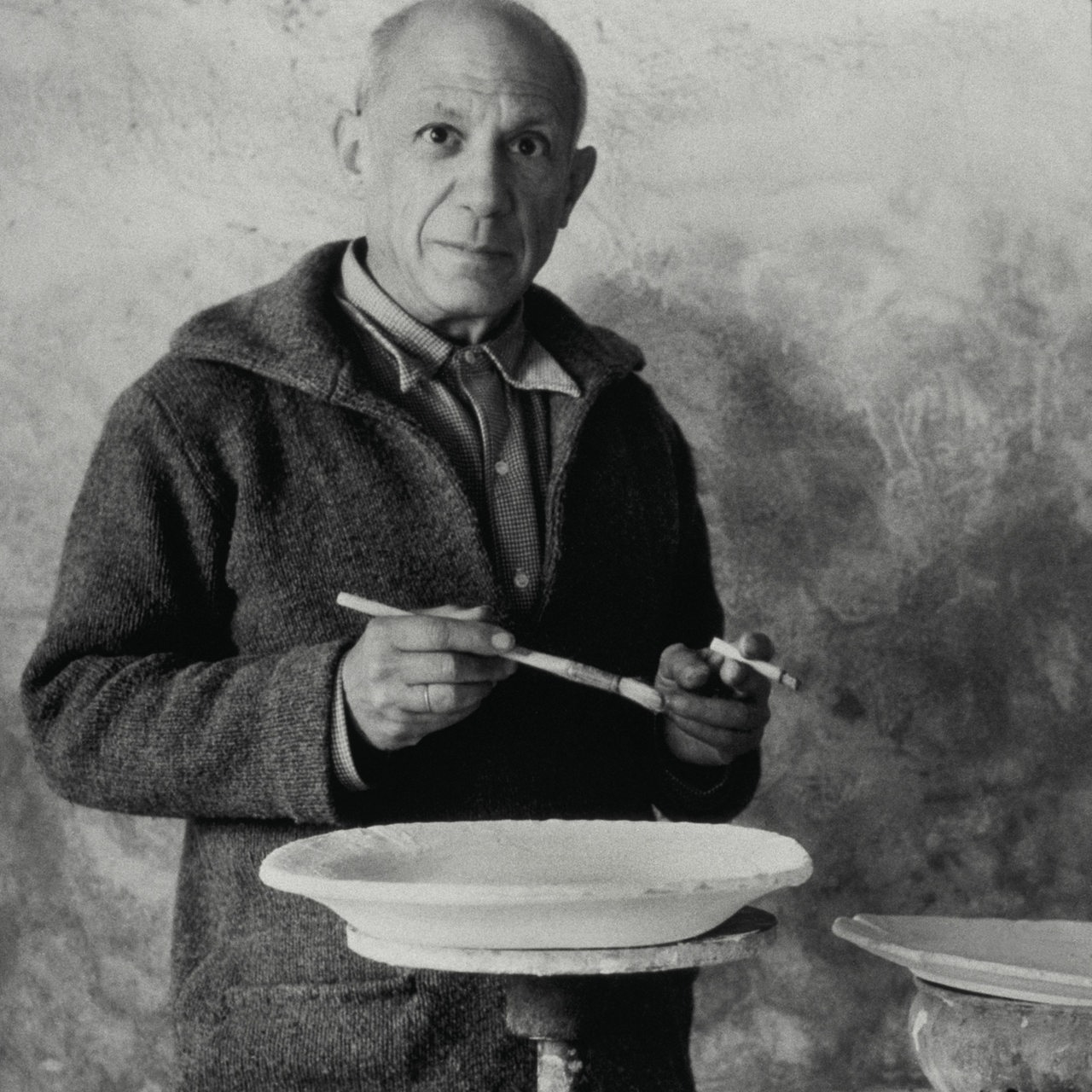 Der Maler Pablo Picasso auf einer Schwarzweiß-Fotografie mit Pinsel