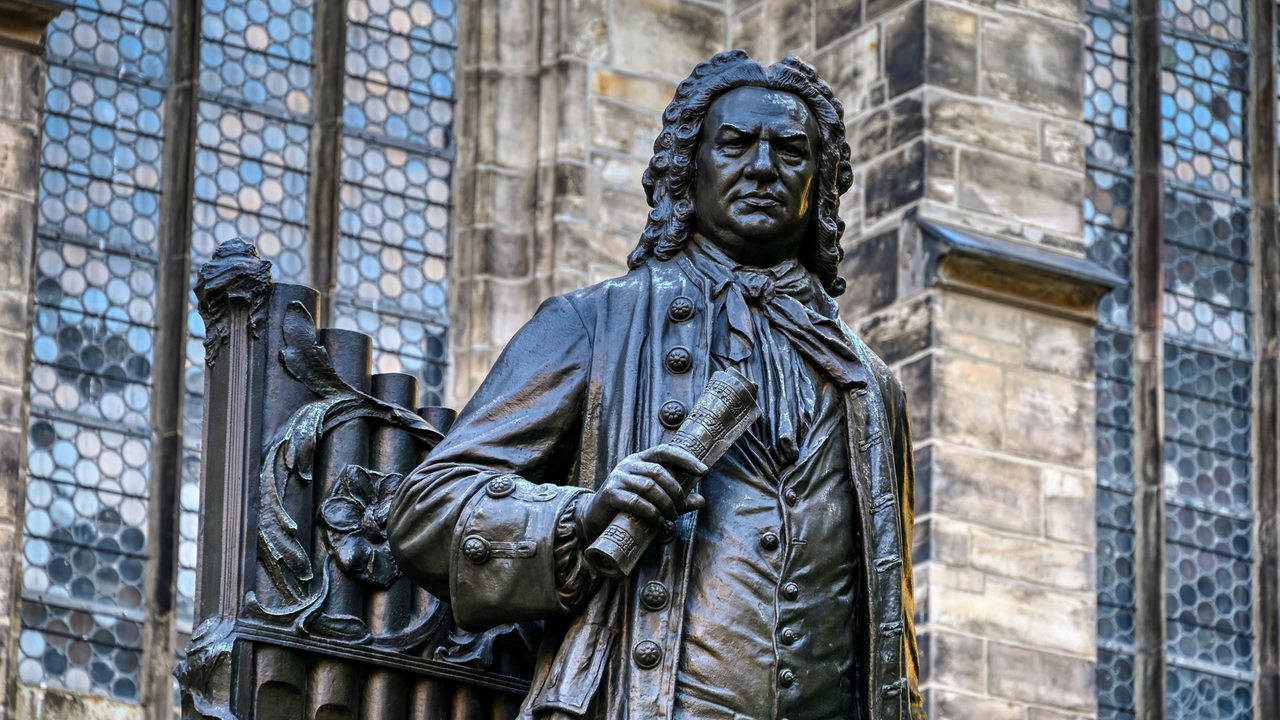 Nahaufnahme des historischen Denkmals des Johann Sebastian Bach in der Leipziger Innenstadt, im Hintergrund die Thomaskirche