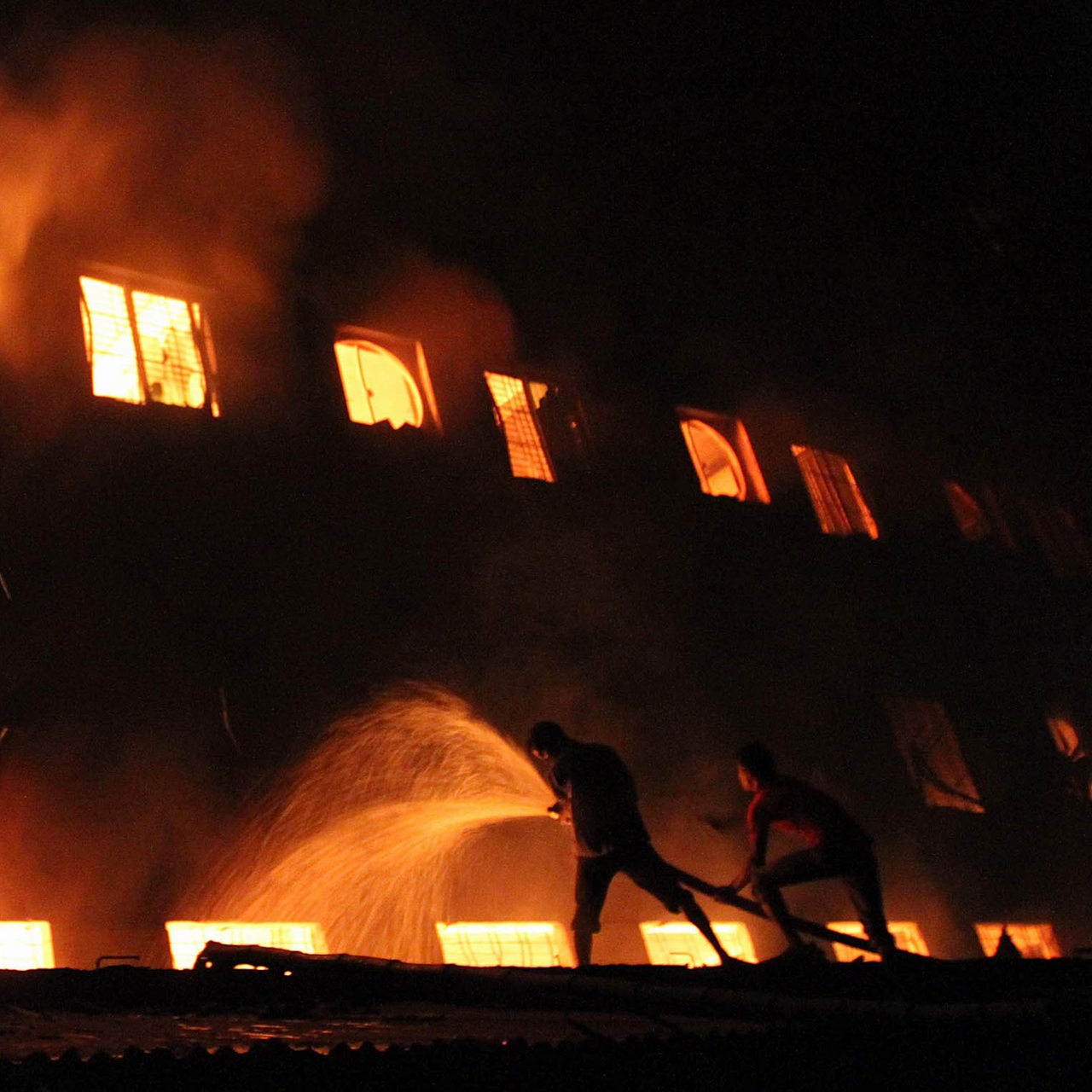 Männer bekämpfen einen großen Brand in einer Textilfabrik in Dhaka.