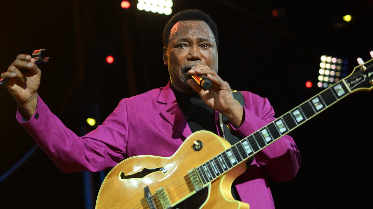 Jazzlegende George Benson auf der Bühne mit Mikro und Gitarre 2022 in Frankreich.