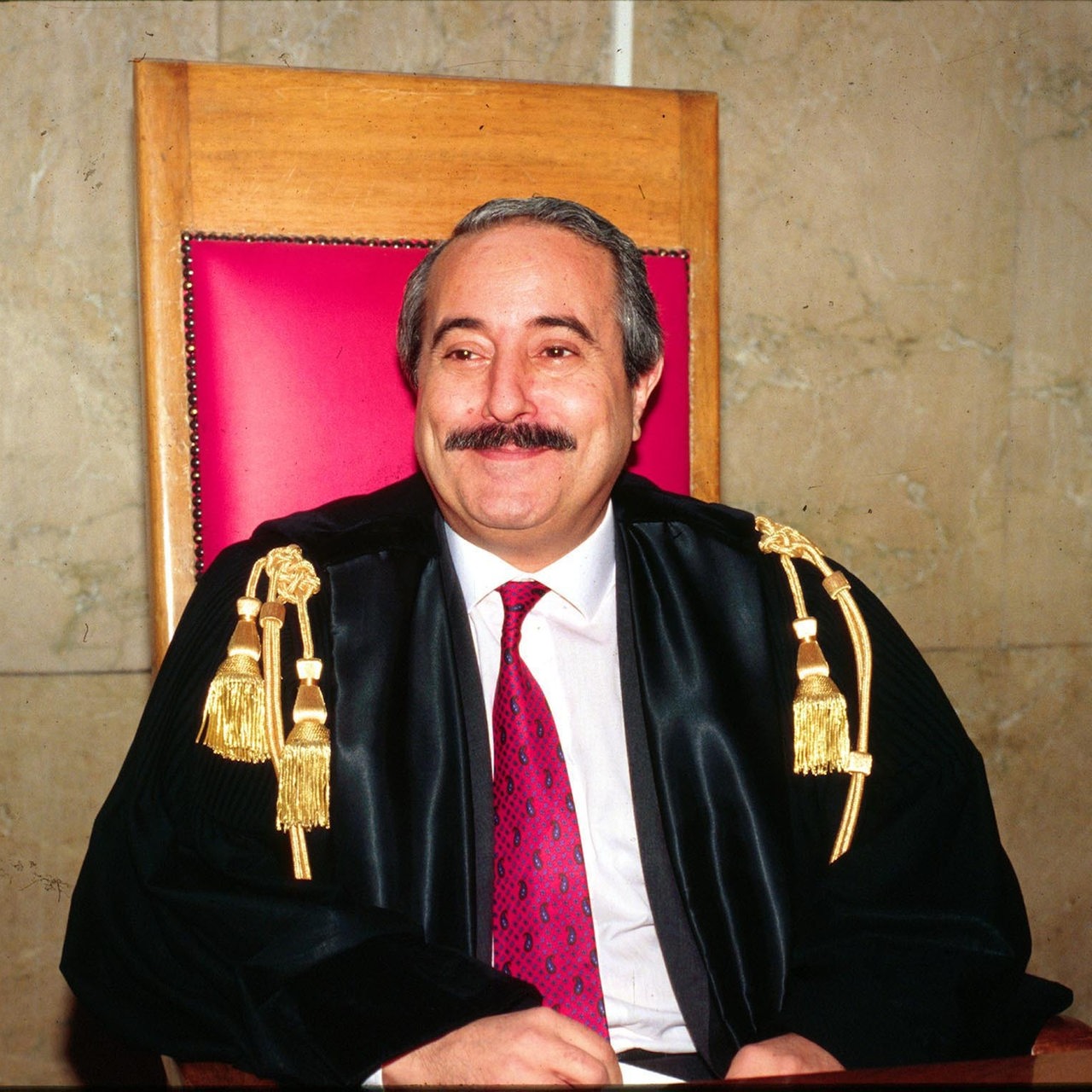 Der Richter und Mafiajäger Giovanni Falcone sitzt lächelnd auf dem Richterstuhl