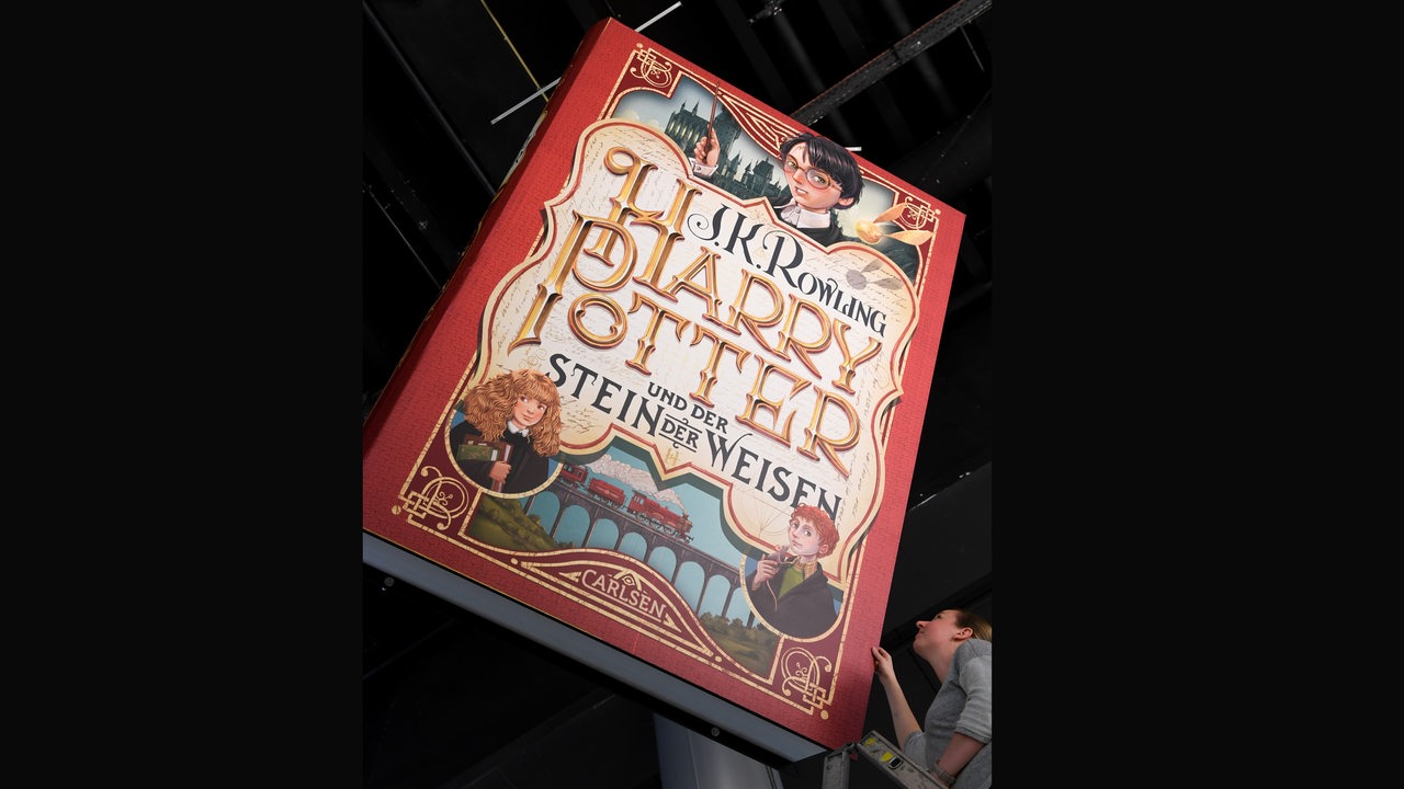 Eine Dekoration in Form eines riesigen Harry-Potter-Buches «Harry Potter und der Stein der Weisen» wird über dem Stand des Carlsen Verlags Hamburg von Maren Gogel ausgerichtet. 
