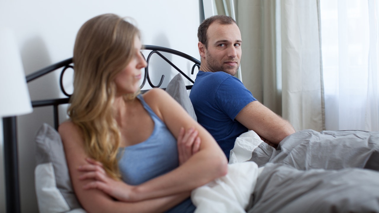 Eine Frau und ein Mann sitzen im Bett und schweigen sich an (gestellte Szene). 