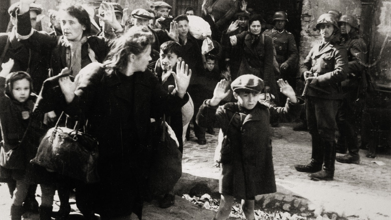 Warschauer Ghettoaufstand April/Mai 1943: Kleiner Bub mit erhobenen Händen, Frauen und andere Kinder kommen aus einem von den deutschen Truppen eroberten Haus. Aus dem Album von SS-Gruppenführer und Polizei-Generalmajor Jürgen Stroop. Photographie, 1943.