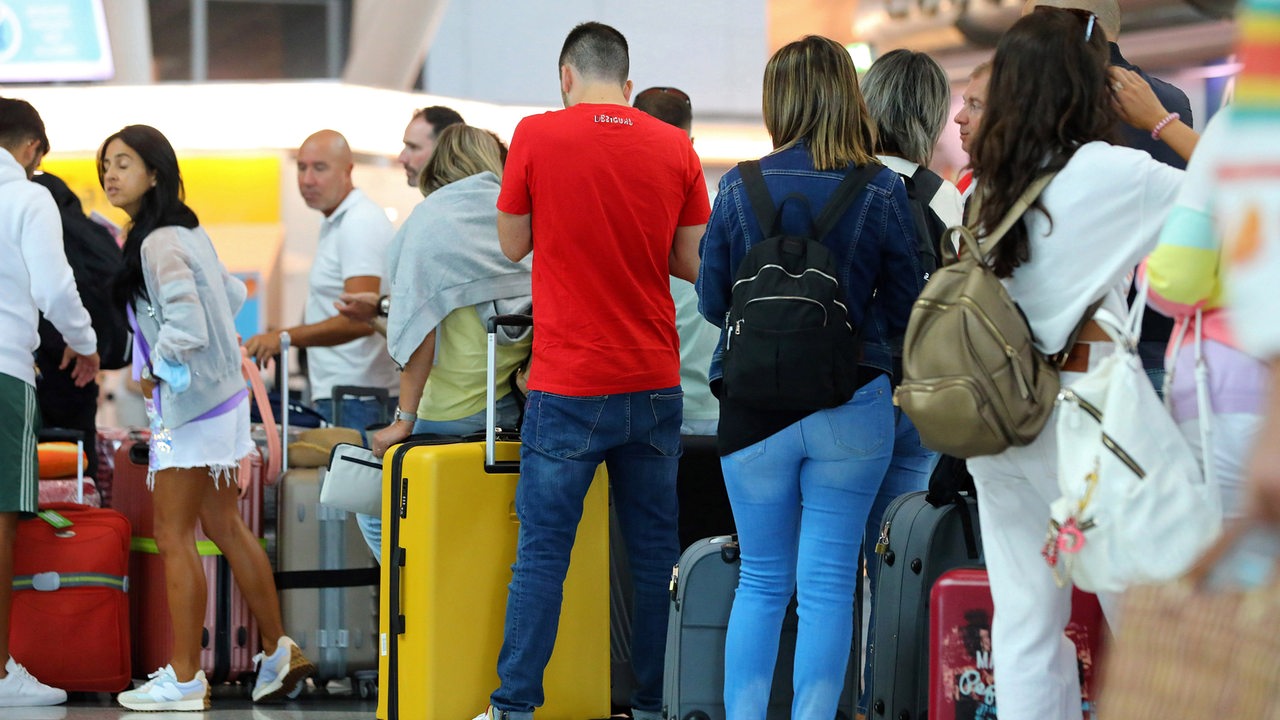 Reisende warten am Flughafen mit ihren Koffern auf ihren Flug