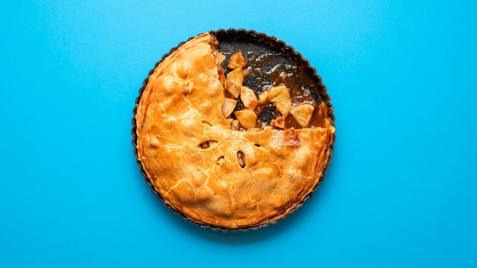 Ein angebrochener Apfeltorte vor blauem Hintergrund
