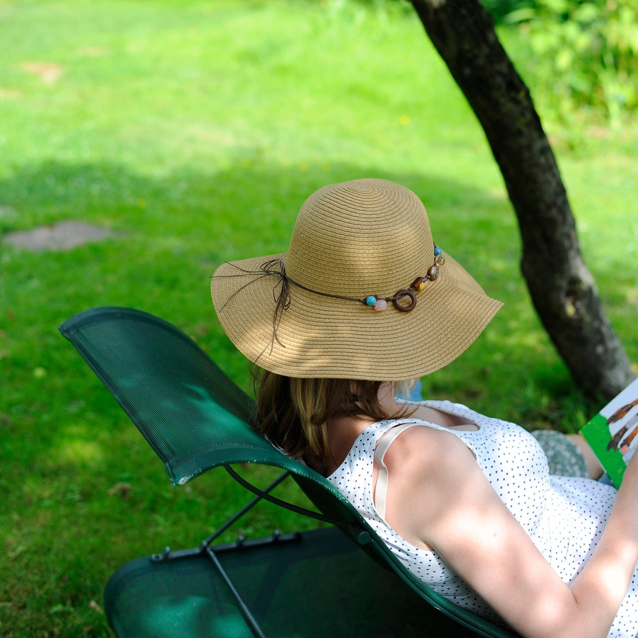 Frau liegt mit Sonnenhut in einem Liegestuhl