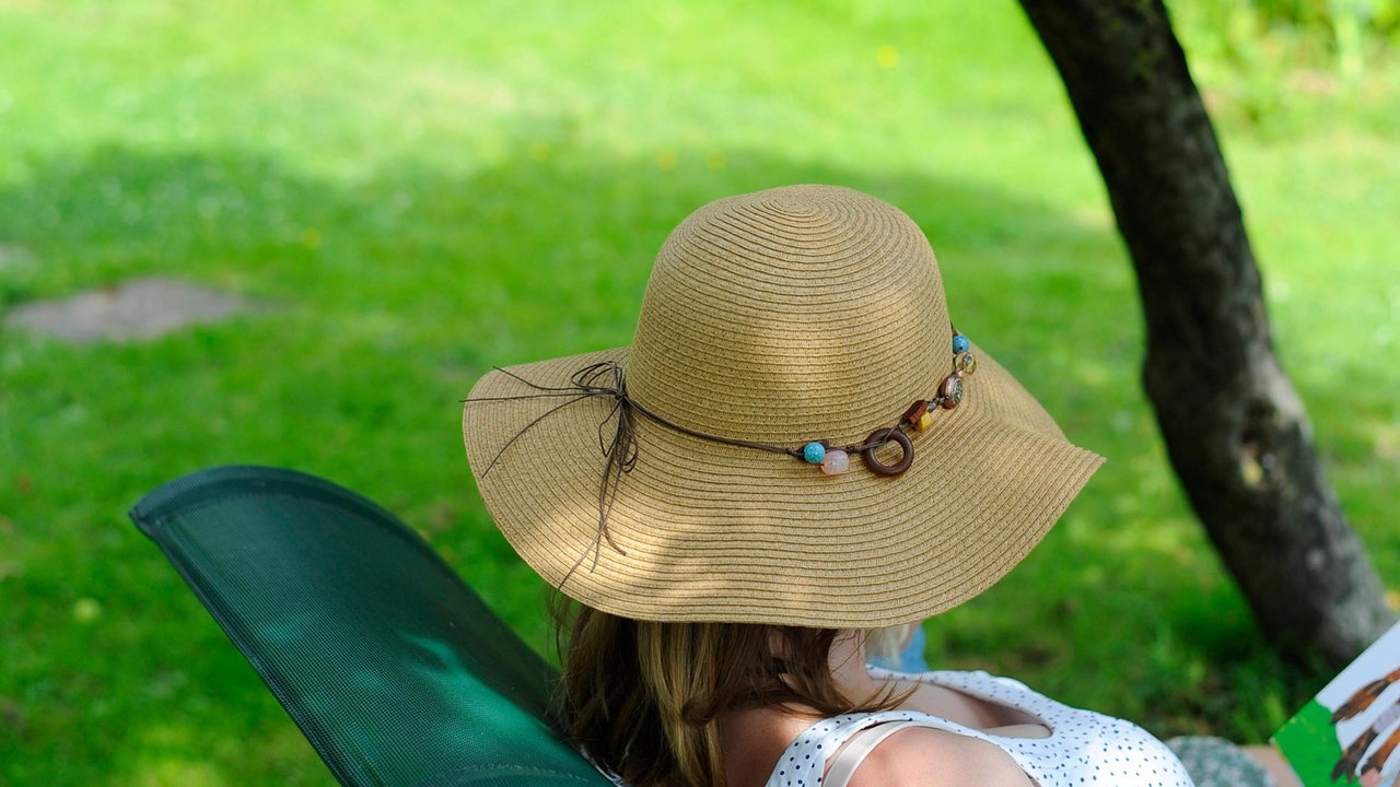 Frau liegt mit Sonnenhut in einem Liegestuhl