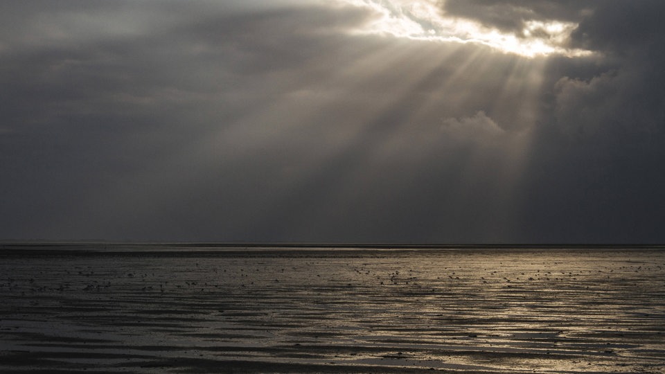 Sonnenstrahlen scheinen durch dunkle Wolken