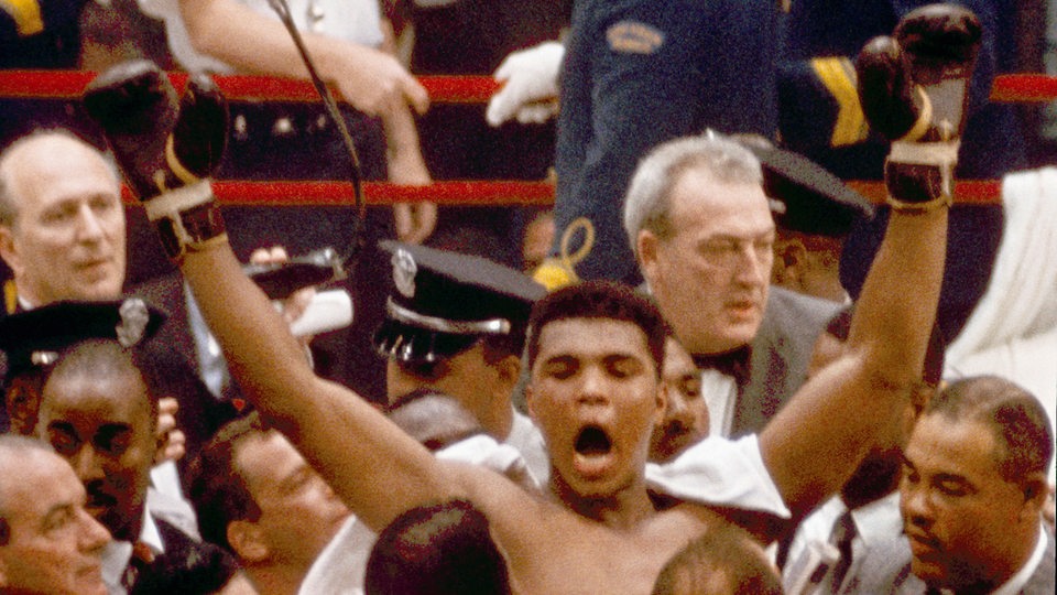 Umringt von Menschen zeigt sich 1964 Cassius Clay in Siegerpose als jüngster Boxweltmeister im Schwergewicht.