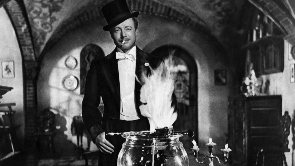 Heinz Rühmann mit Zigarette und Zylinder vor der "Feuerzangenbowle" aus dem gleichnamigen Film.