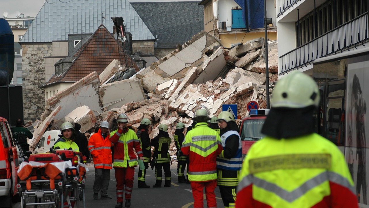 Feuerwehr und Rettungskräfte stehen am eingestürzten historischen Stadtarchiv in Köln.