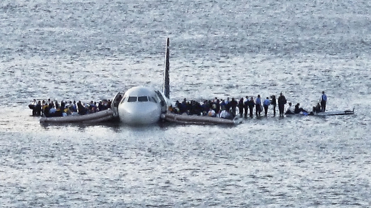 Passagiere stehen auf den Tragflächen einer notgewasserten Maschine auf dem Hudson River 2009