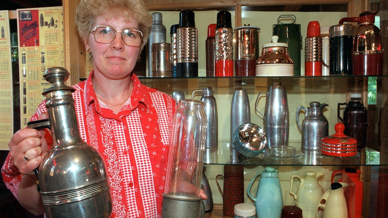 Aus dem Museum in der ehemaligen Schleiferei für Glasprodukte in der Gemeinde Glashütte bei Baruth zeigt eine Mitarbeiterin historische Thermoskannen