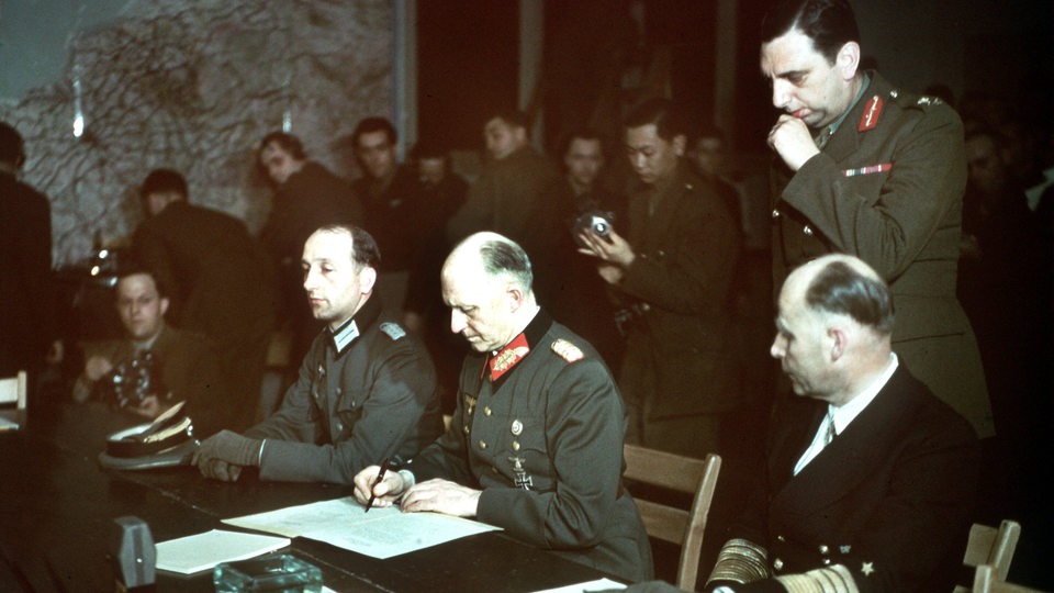 Generaloberst Alfred Jodl (m) unterzeichnet die Kapitulation, sein Adjudant Oberst Wilhelm Oxenius, Admiral Hans Georg von Friedeburg,