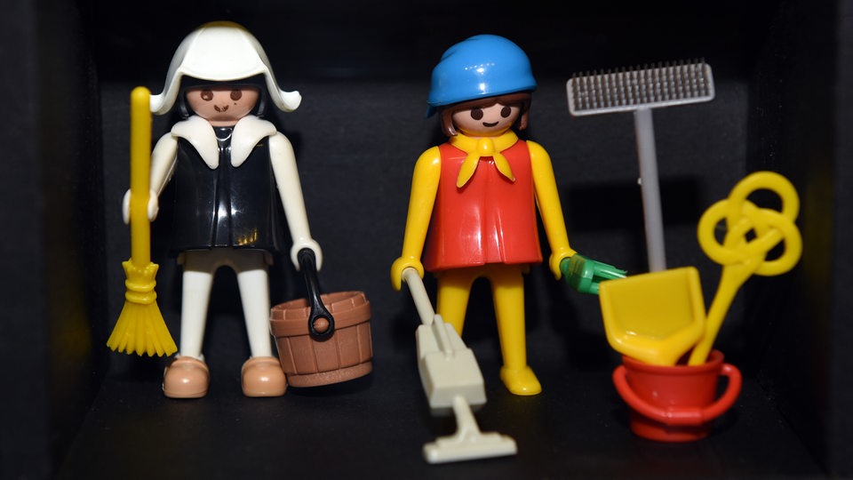 Die ersten Playmobil-Figuren zeigen einen Straßenarbeiter und eine Hausfrau mit Geräten von 1974
