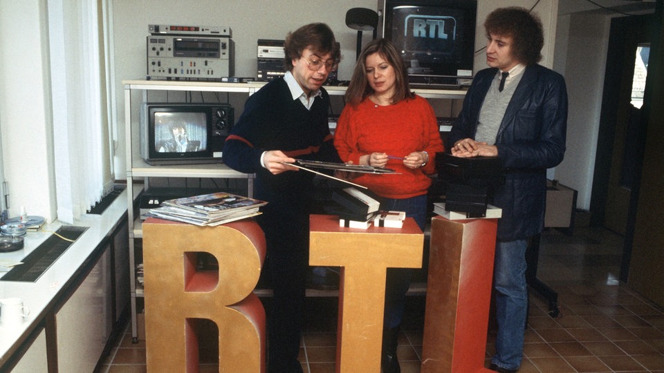 Produktionsleiter Horst Tempel, Musikkoordinatorin Angelika Schimpf und Moderator Ilf Bennet bei einer Arbeitsbesprechung in der Luxemburger Sendezentrale von RTL im Dezember 1983