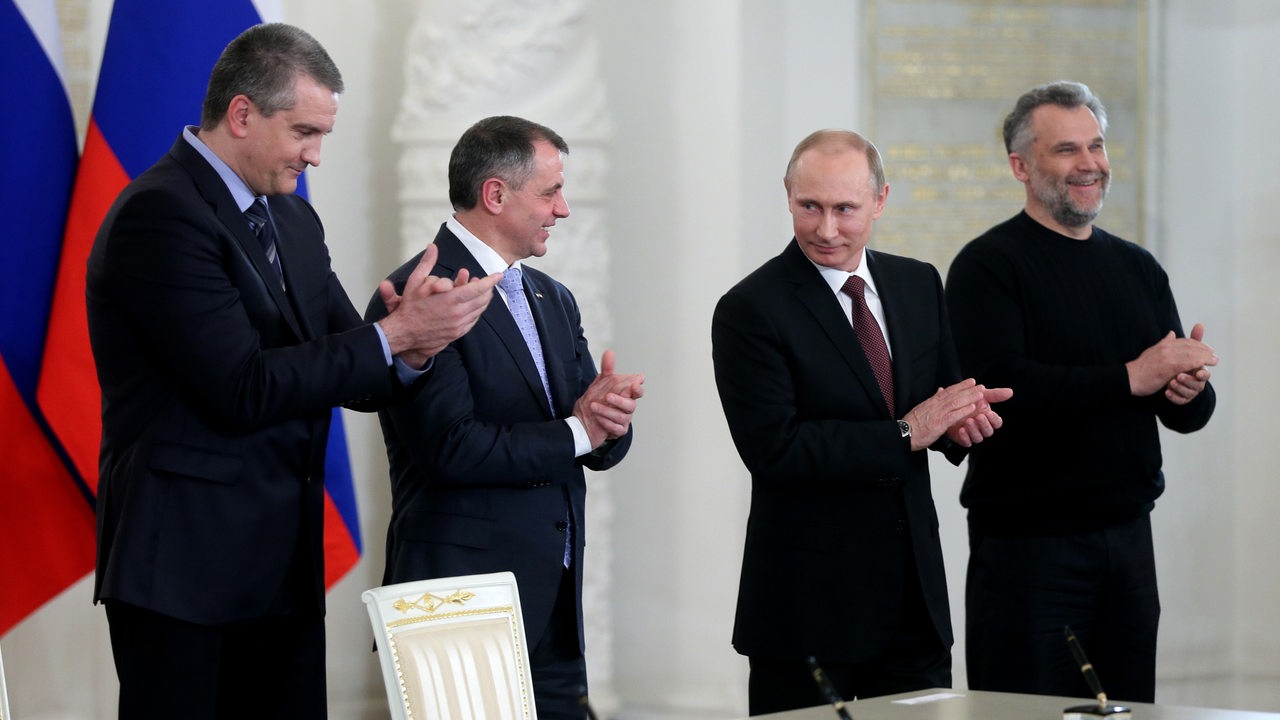 Minister der Krim Sergei Aksenov und Vladimir Konstantinov, der russische Präsident Putin und Alexei Chalyi klatschen nach Unterzeichung des Referendum 2014 zwischen der Krim und Russland in die Hände.