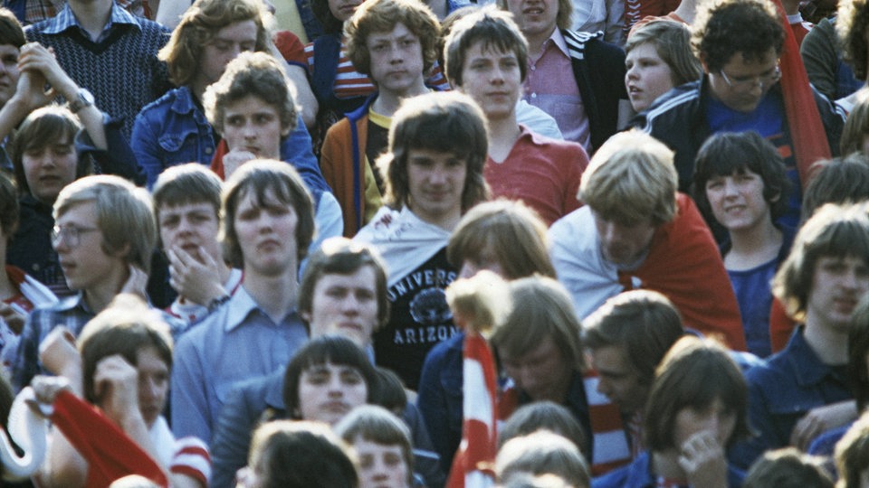 Jugendliche in den 70er Jahren in einem Fußballstadion.