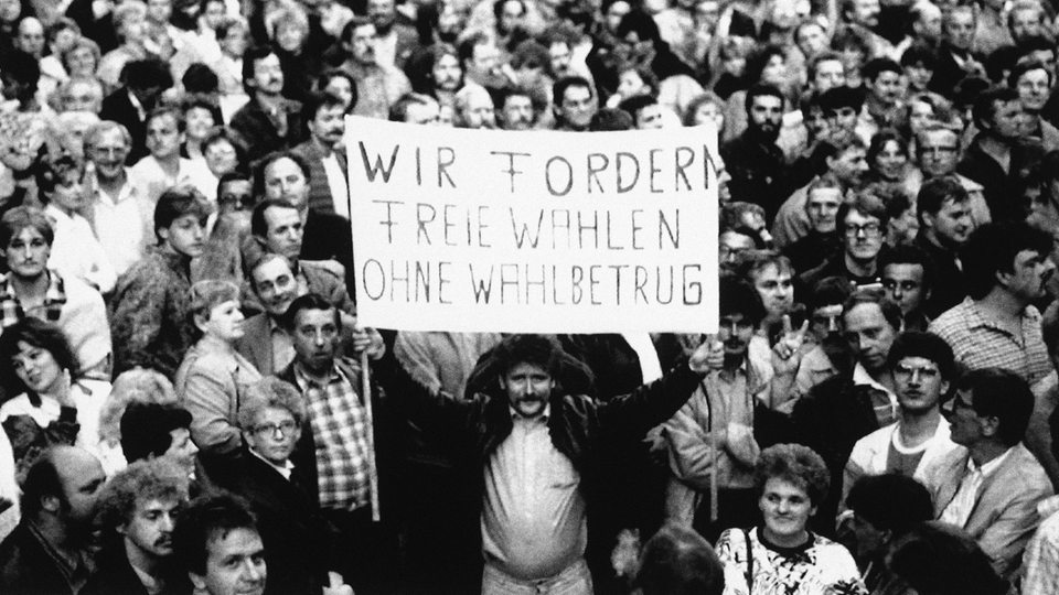 Während einer Montagsdemonstration 1989 in Leipzig fordern die Menschen auf einem Transparent "Freie Wahlen ohne Wahlbetrug"