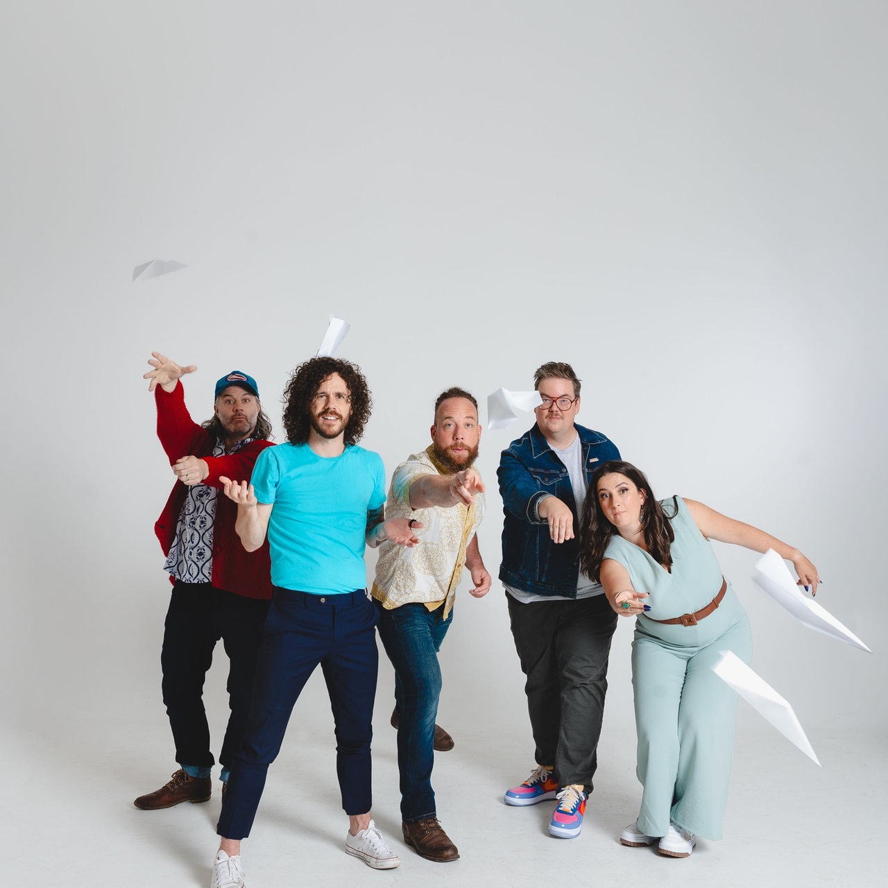 Fünf Personen stehen nebeneinander mit Papierfliegern
