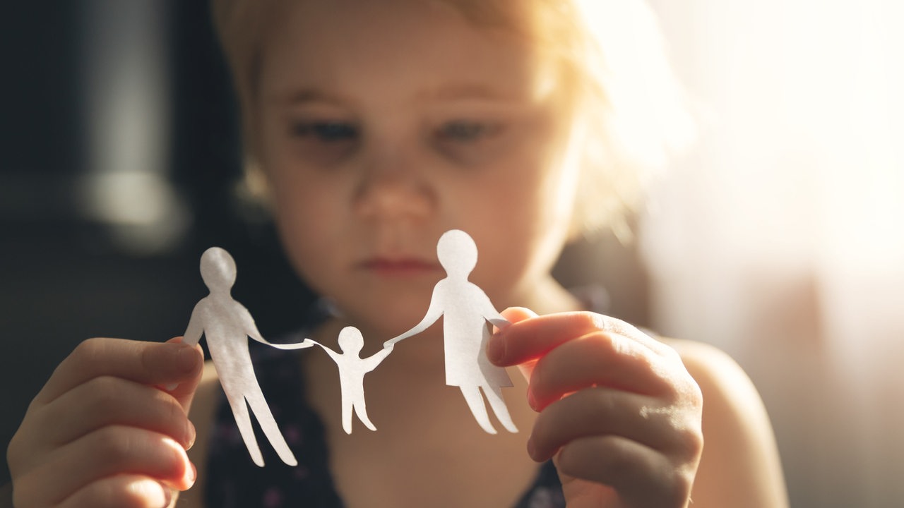 Kleines Mädchen mit gebastelter Papierfamilie in den Händen (Symbolbild)