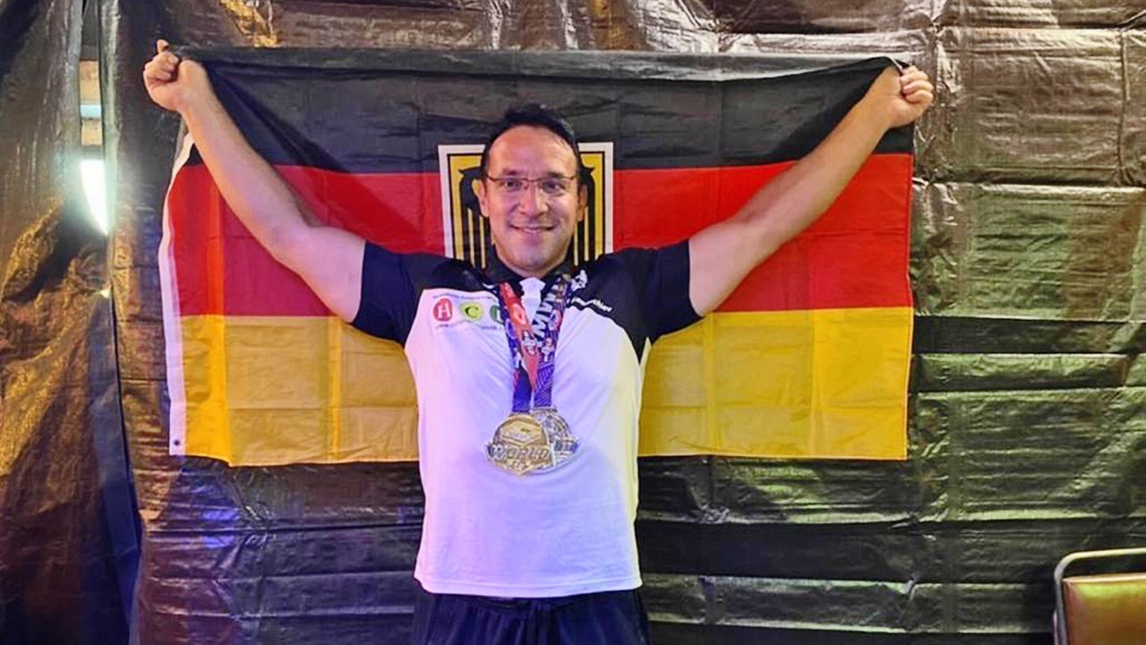 Der Weltmeister im Armdrücken Roland Kamtschiev hält die Deutschlandflagge hoch