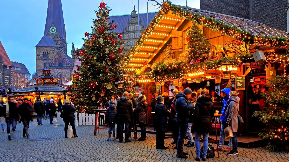 Beleuchteter Glühweinstand auf dem Bremer Weihnachtsmarkt, im Hintergrund die Liebfrauenkirche.